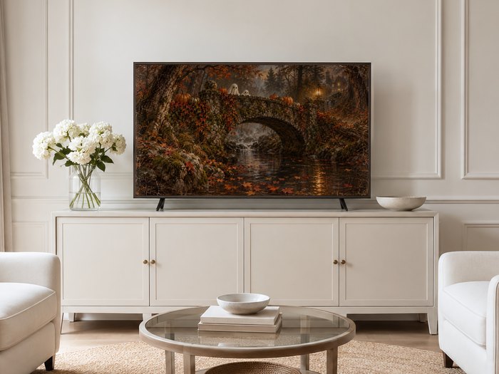 Autumn Ghosts on the Stone Bridge Frame TV art shown on a neutral living room wall with cream panelled walls, a long cream sideboard, white hydrangeas in a glass vase and pale armchairs on a jute rug.