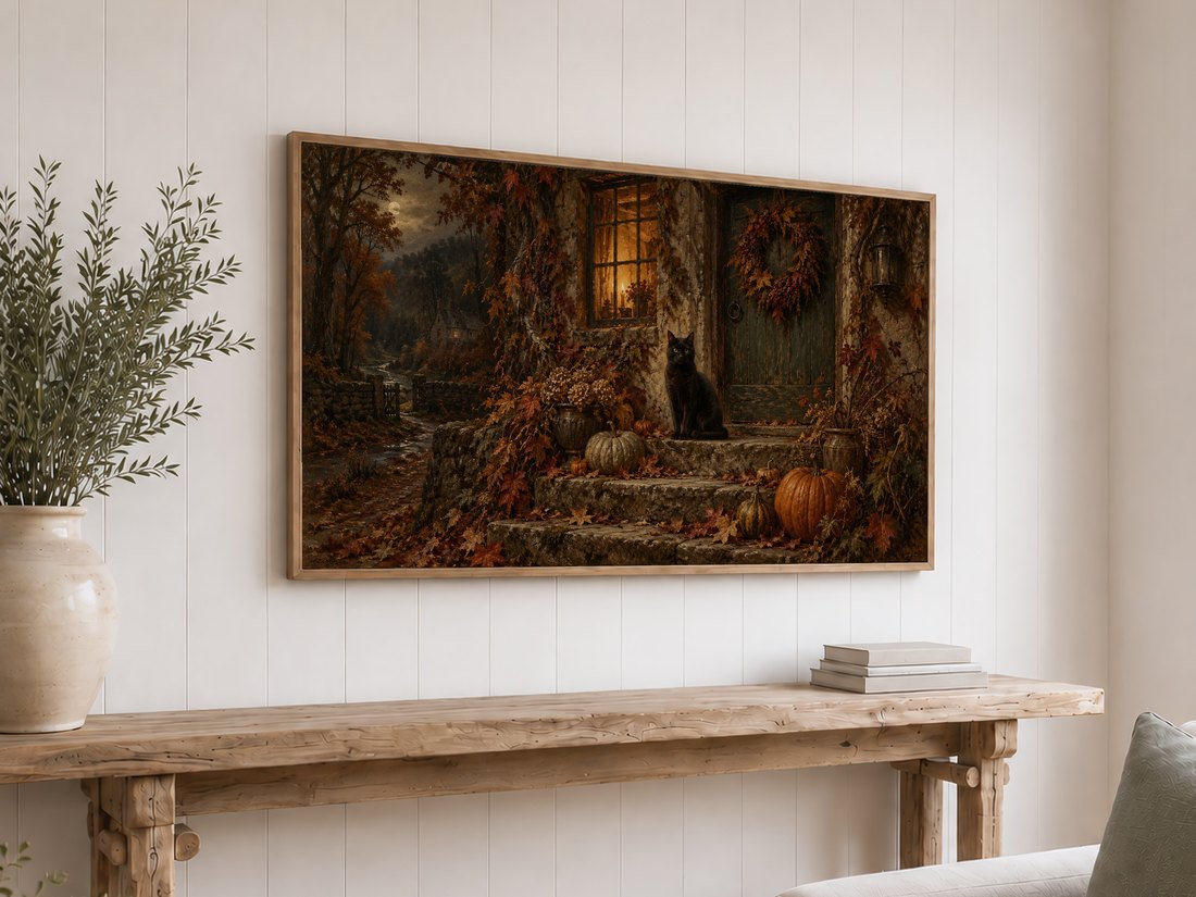 Black cat gothic landscape shown on Frame TV above rustic reclaimed-wood console table with olive branches in cream ceramic vase and neutral stacked books on white shiplap wall.