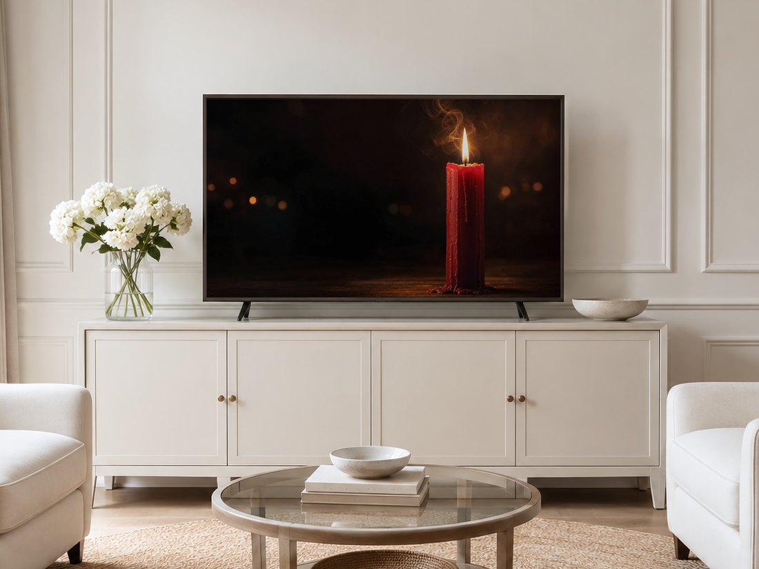 Moody red candle artwork shown on a Frame TV in a neutral living room with a cream panelled wall, long sideboard, white hydrangeas, glass coffee table and pale armchairs on a jute rug.