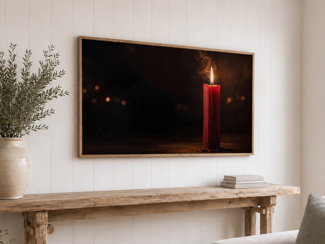 Red candle wall art on a light oak framed TV against a white shiplap wall, above a reclaimed-wood console with olive branches in a ceramic vase and a stack of neutral books.