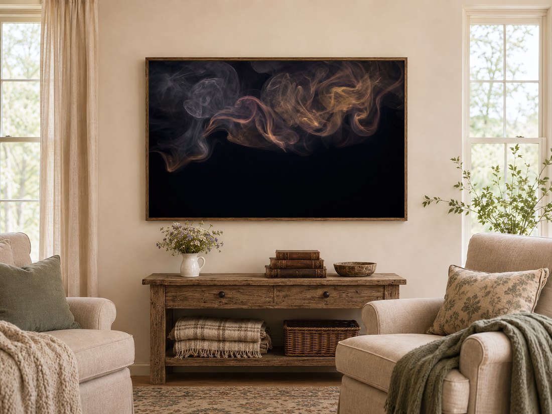 Moody smoke abstraction in a dark reclaimed-wood frame above a rustic console table with wildflowers and leather books, set in a warm farmhouse living room with cream armchairs and sage cushions.