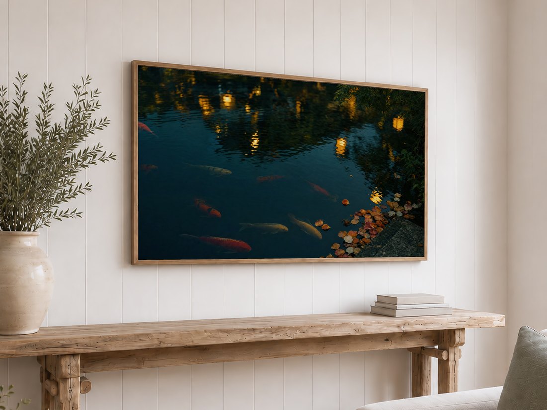 Koi pond art glowing softly on a Frame TV above a reclaimed-wood console table with olive branches and neutral books, set against a white shiplap wall for a calm, natural feel.