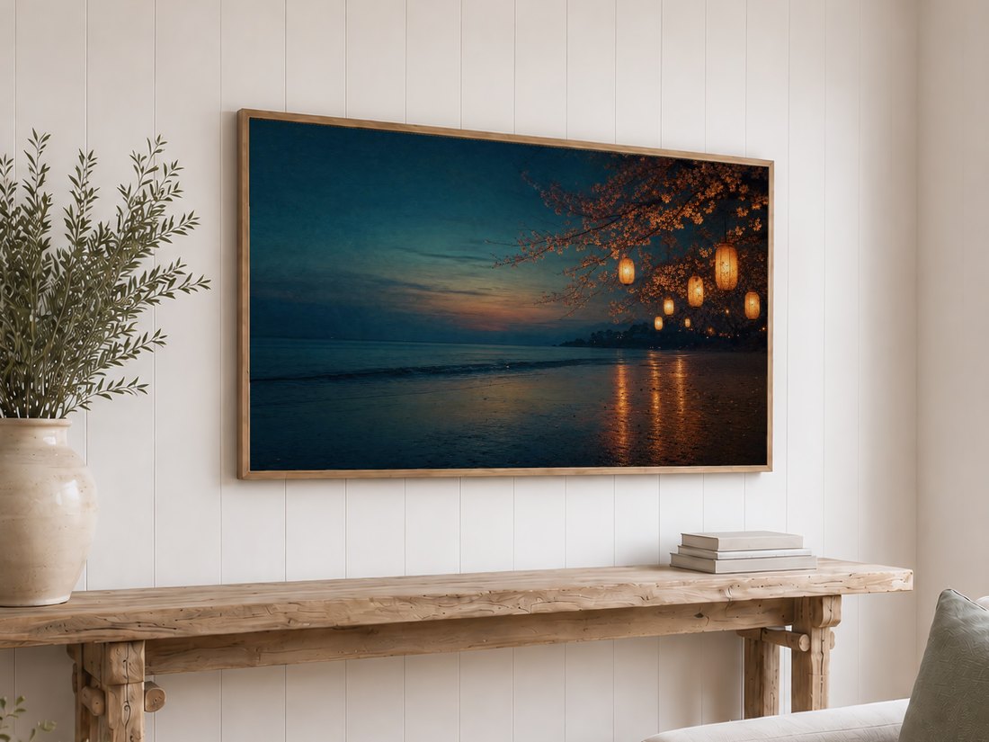Glowing lantern beach artwork on a light oak framed TV against a white shiplap wall, set above a reclaimed-wood console table with olive branches in a cream vase and stacked neutral books, a warm coastal touch for a relaxed living space.