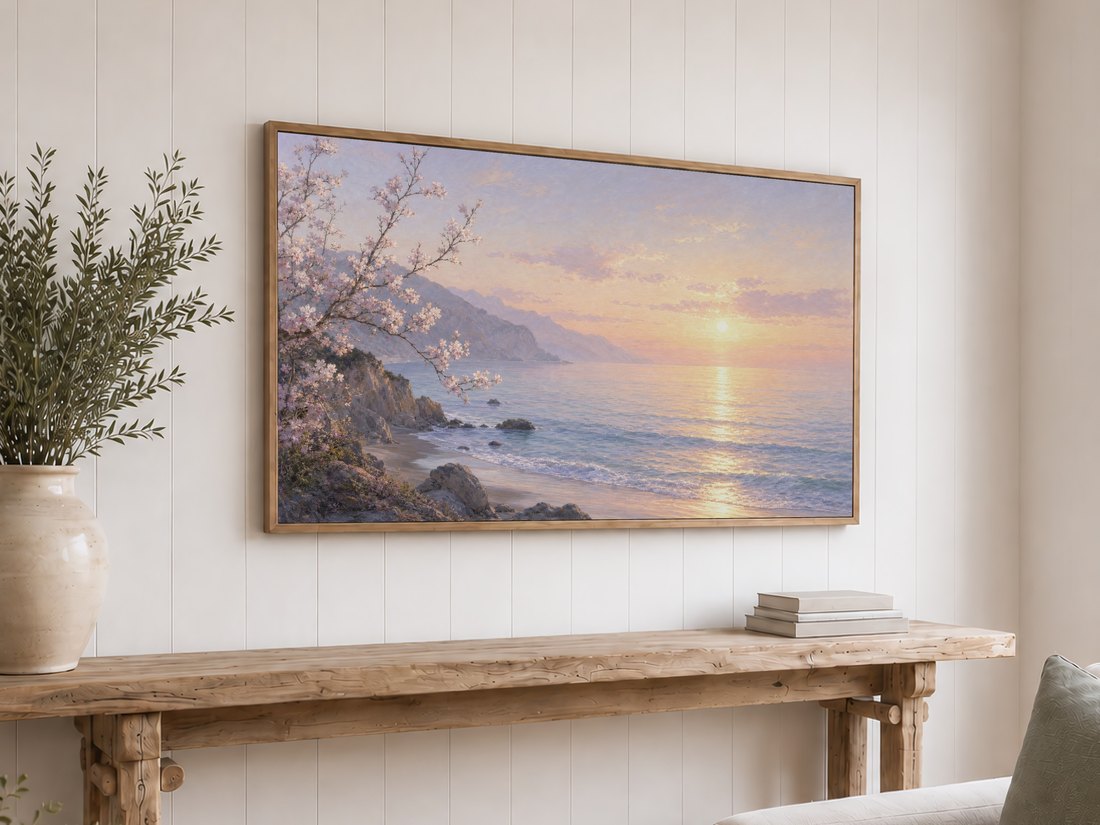 Coastal blossom sunrise art displayed on a light oak framed TV above a reclaimed-wood console with olive branches and neutral books, set against a white shiplap wall for cottage style decor.