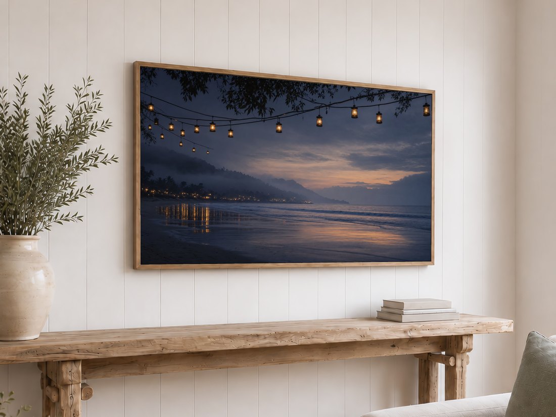 Foggy coastal art glowing on a light oak framed TV above a reclaimed-wood console with olive branches and neutral books, set against a white shiplap wall.
