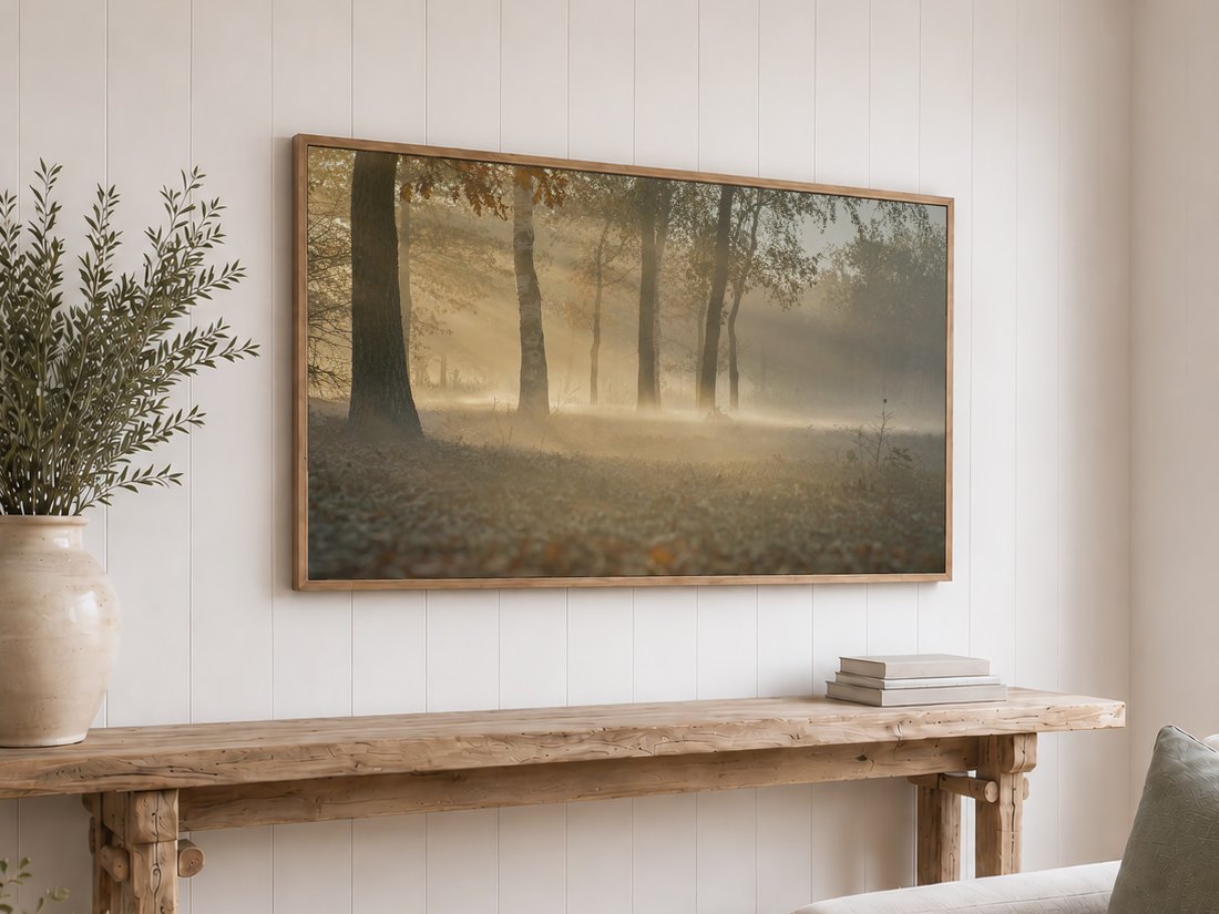 Foggy birch and oak forest scene with soft morning light shown on a Frame TV above a reclaimed-wood console with olive branches, set against a white shiplap wall.
