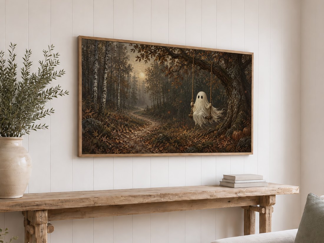 Hauntingly peaceful forest scene with ghost and pumpkins displayed on a Frame TV in a light oak frame above a reclaimed-wood console with cream ceramic vase and books.