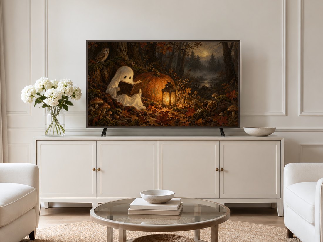 Spooky autumn forest scene with ghost, pumpkin and lantern shown on Frame TV above glass coffee table in neutral living room with cream sideboard, white hydrangeas and pale armchairs.