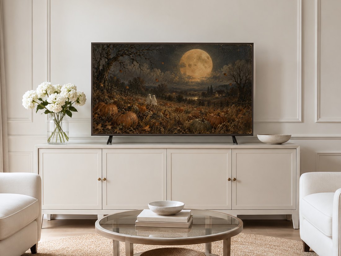 Ghosts Beneath the Harvest Moon shown on a Frame TV in a neutral living room with cream panelled walls, a long cream sideboard with brass knobs, white hydrangeas in a glass vase, and pale armchairs on a jute rug