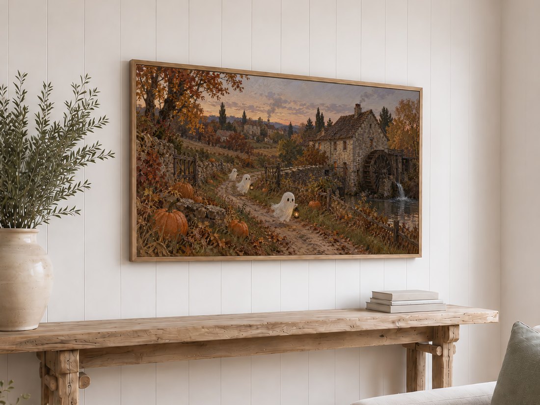 Autumn pumpkin and ghost landscape on Frame TV mounted on white shiplap above a rustic reclaimed-wood console table with olive branches in a cream ceramic vase and stack of neutral books, creating a harvest-ready display