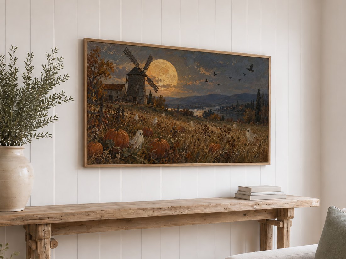 Golden moon windmill and harvest scene artwork displayed on white shiplap above a light oak framed TV and rustic console table with cream ceramic vase of olive branches and neutral books.