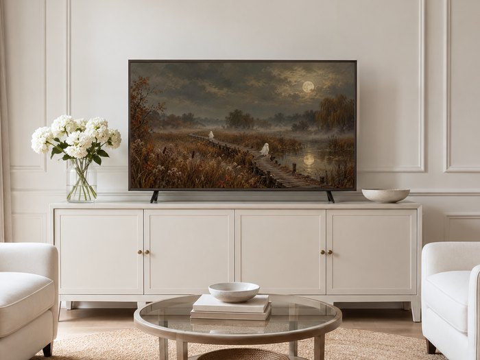 Moody autumn landscape with ghostly figures on a moonlit boardwalk shown on a Frame TV mounted on a neutral cream panelled wall above a cream sideboard with brass knobs and white hydrangeas