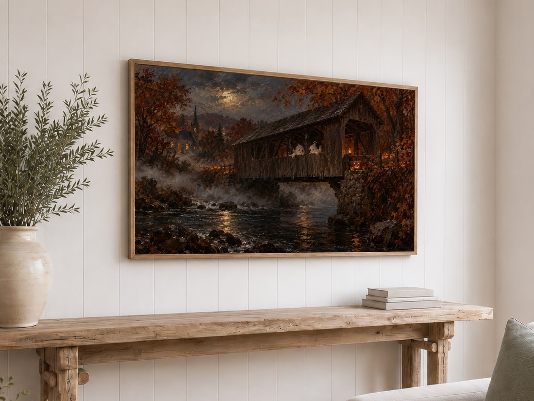 Ghostly figures on a misty bridge under moonlight with amber foliage and a distant church, shown on a Frame TV in a light oak frame above a reclaimed-wood console table with cream ceramics and olive branches on a white shiplap wall.