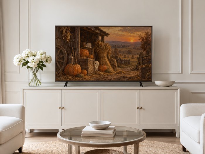 Autumn harvest Frame TV art displayed on a neutral living room wall with cream panelled wall, cream sideboard with brass knobs, white hydrangeas in glass vase, round glass coffee table and pale armchairs on jute rug.