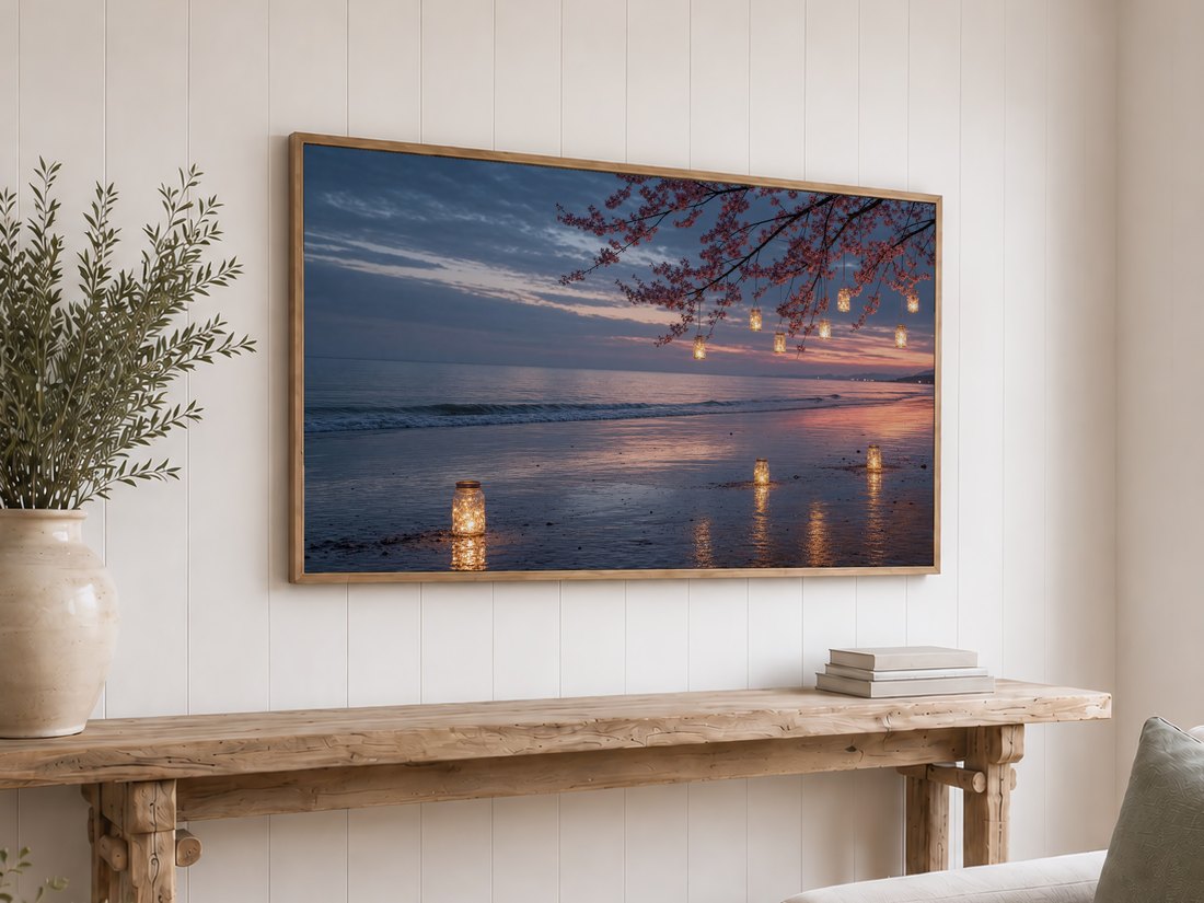 Cherry blossom shoreline art with glowing lantern jars on a Frame TV against a white shiplap wall, above a reclaimed-wood console with olive branches and neutral books.