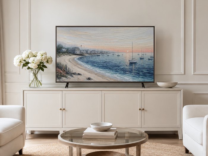 Coastal harbor sunrise Frame TV art in a neutral living room with a cream panelled wall, cream sideboard, white hydrangeas, glass coffee table and pale armchairs on a jute rug.